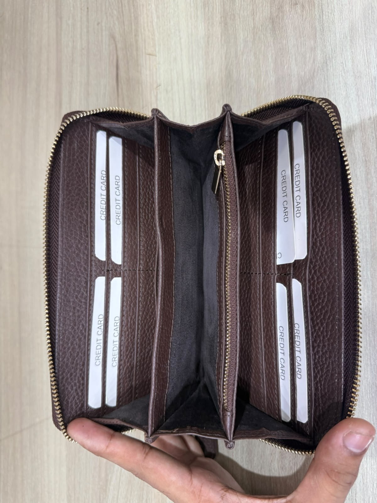 Brown leather zip wallet opened to show card slots and central zip pocket